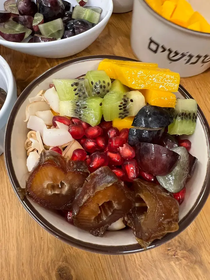 Pitted dates in a bowl with mango, kiwi, pomegranate and coconut